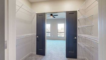 a walk-through closet with dark grey double doors and built-in wire shelving