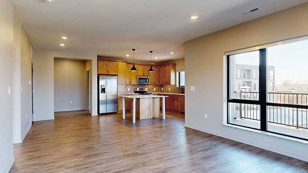 a spacious living room with a kitchen in the background