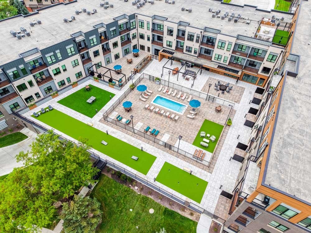An aerial view of a courtyard with a pool and outdoor yard games.