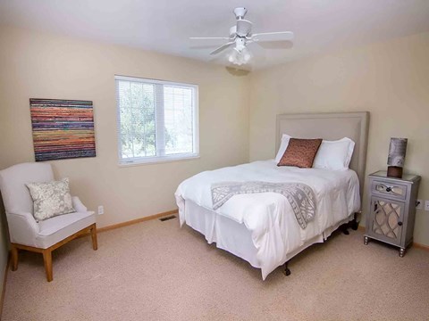 a bedroom with a white bed and a ceiling fan