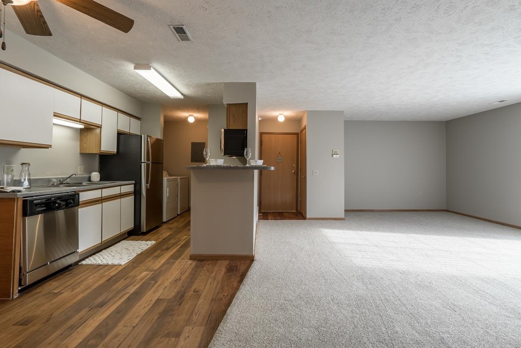 A kitchen with wooden floors that opens to living room