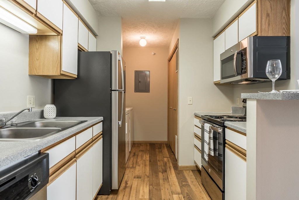 A kitchen with stainless steel appliances and white and oak cabinets.