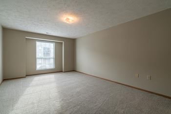 A bedroom with a carpeted floor and a window with blinds.