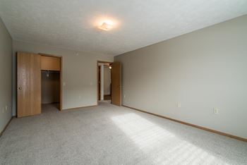 A bedroom with a carpeted floor and a ceiling light.
