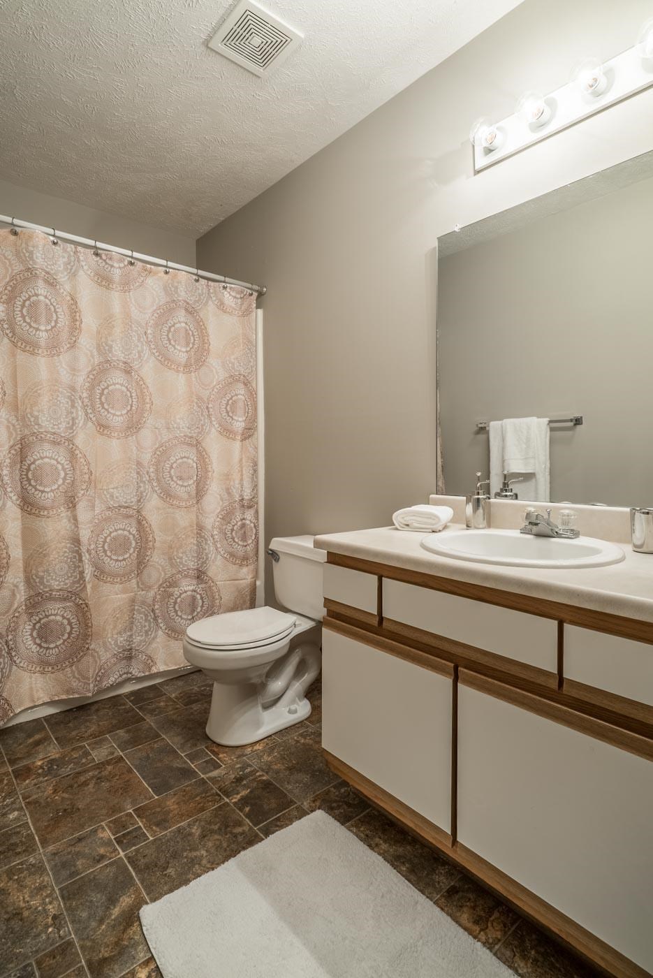 A bathroom with a toilet, sink, and shower curtain.