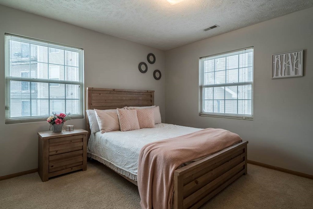 A bedroom with a bed, nightstand, and window.