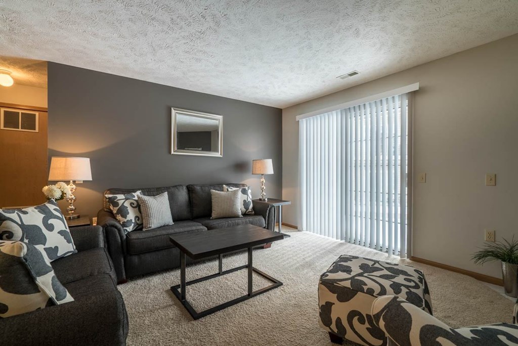 A living room with a grey couch, a coffee table, and a lamp.
