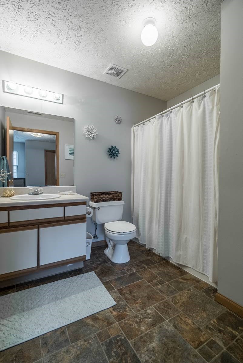 A bathroom with a toilet, sink, and shower curtain.