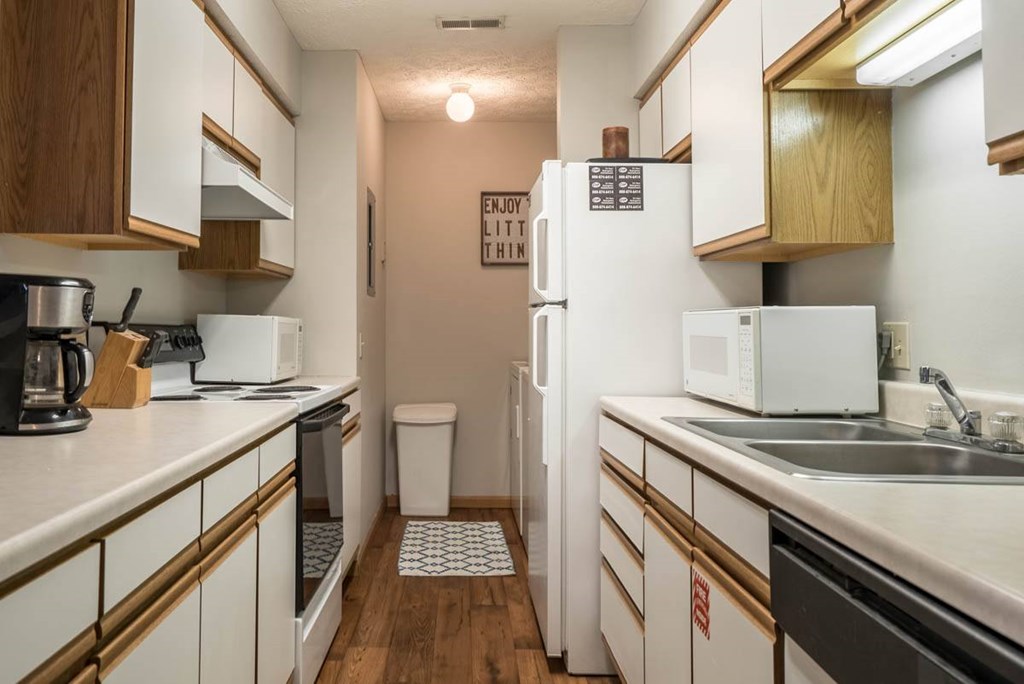 A kitchen with white appliances and white and oak cabinets.