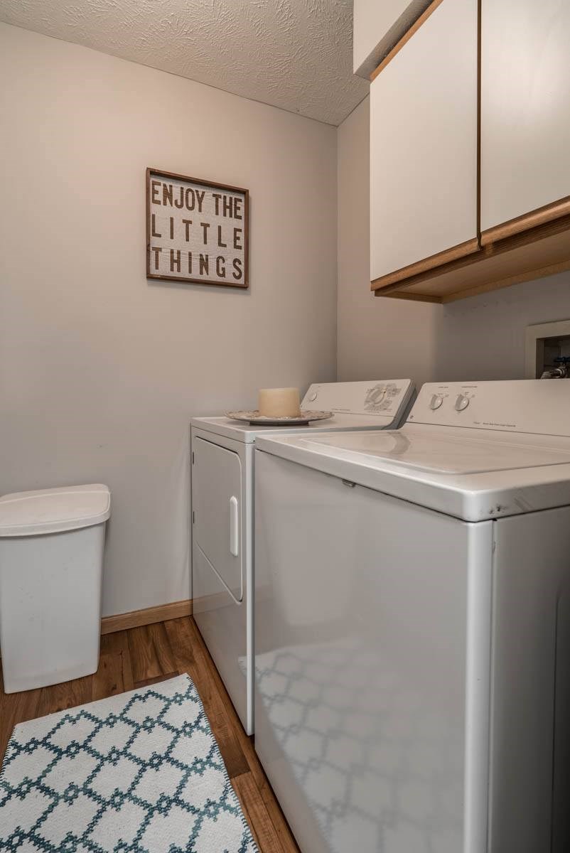 A laundry room with a washer and dryer and cabinet above them