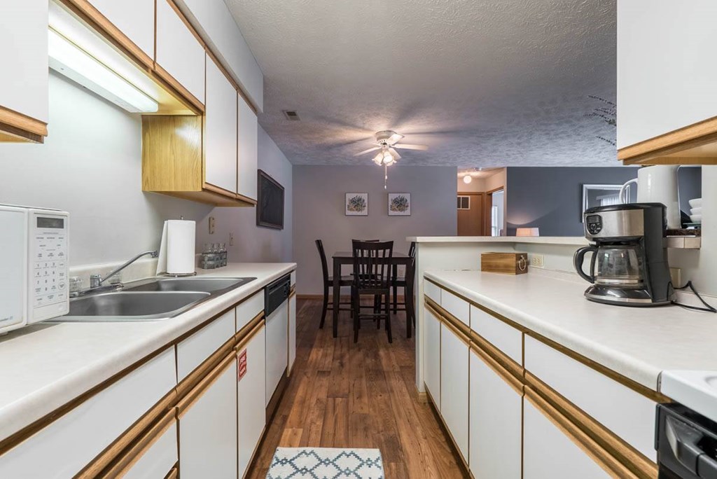 A kitchen with white cabinets and a wooden floor.