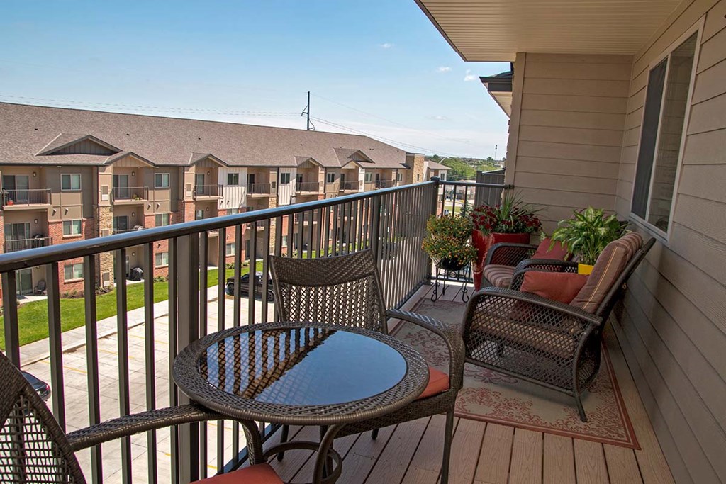 A balcony with a table and chairs overlooking apartment buildings.