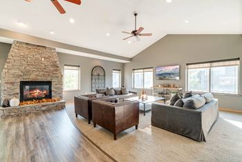 a clubhouse tv lounge with large couches and armchairs, with a fireplace