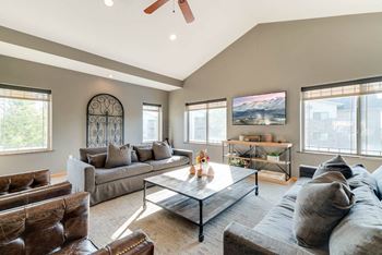 a clubhouse tv lounge with large couches, arm chairs, and a coffee table