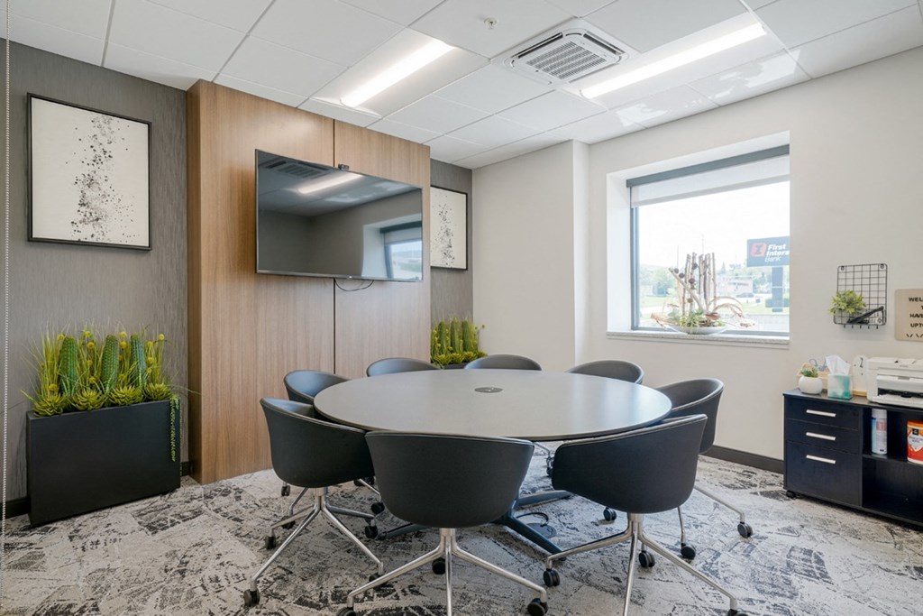 a conference room with a round table and chairs and a television