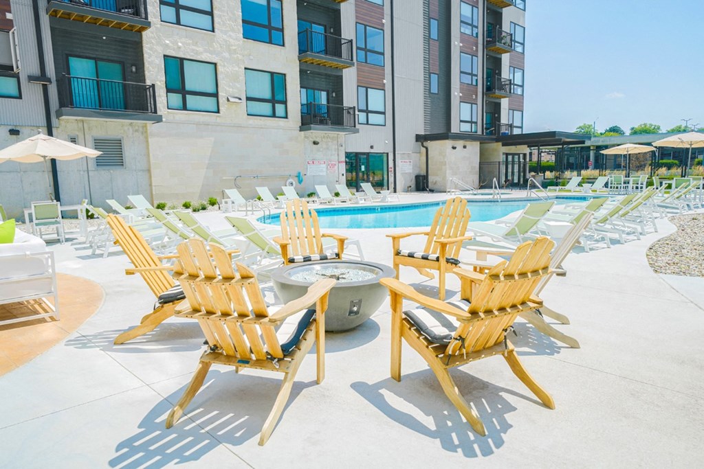 an outdoor pool with lounge chairs and a fire pit