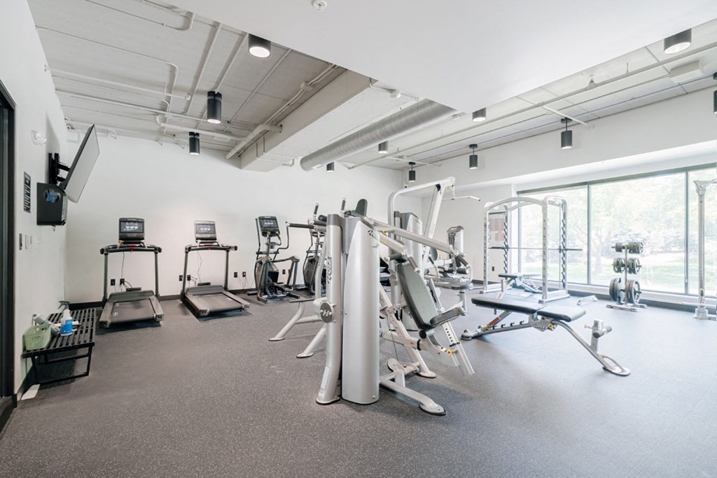 a gym with various exercise equipment in a room with windows