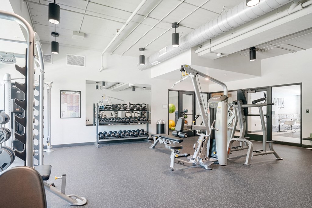 a gym with weights and other exercise equipment in a building with white walls