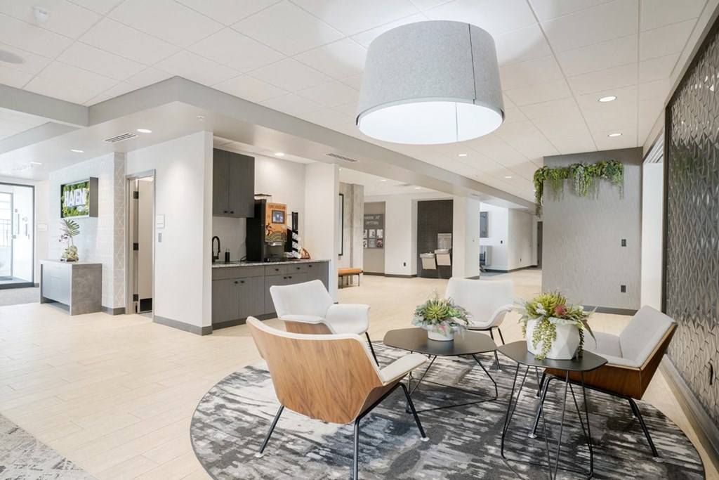 a main lobby area with chairs and a table and coffee bar