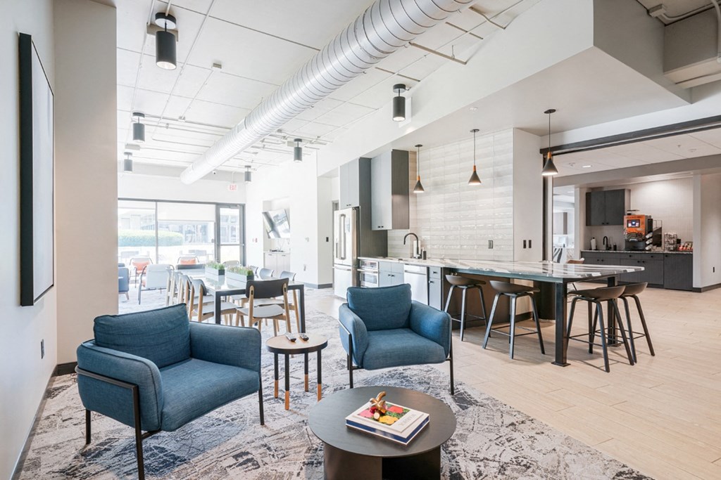 a living room with blue chairs and a kitchen with a table and chairs