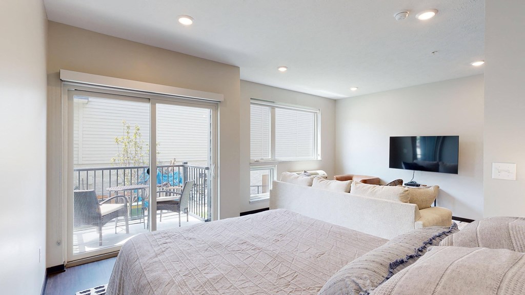 a studio home with a large bed and a tv on the wall