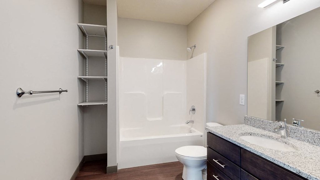 Bathroom with dual sink counter tops, a bathtub, and shelves for additional storage at Haven at Uptown in Lincoln, NE