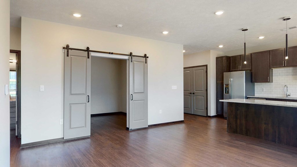 Living space with sliding barn doors leading to an office space in the Melody floor plan at Haven at Uptown in Lincoln, NE