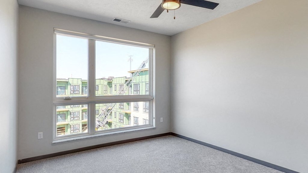 Bedroom with large window and ceiling fan in the Melody floor plan at Haven at Uptown in Lincoln, NE