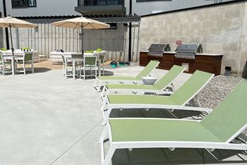 Row of light green lounge chairs and table with umbrellas near the pool at Haven at Uptown.