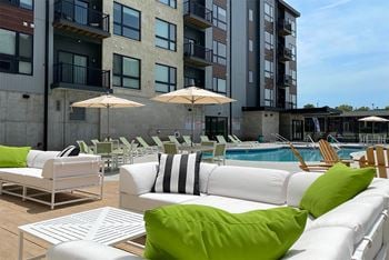 White outdoor sofa with decorative pillows near the pool outside Haven at Uptown.