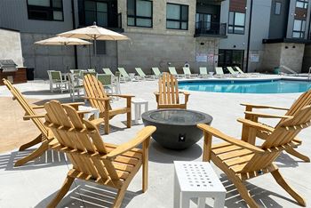 Wood Adirondack chairs arranged around a firepit near an outdoor pool at Haven at Uptown.