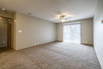 Empty living room with carpet, ceiling fan, and sliding glass door - Photo Gallery 35