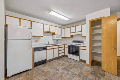 A kitchen with white appliances and wooden cabinets.