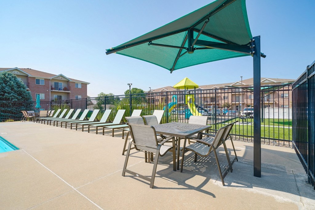 table seating with overhead umbrella for shade on the pool deck