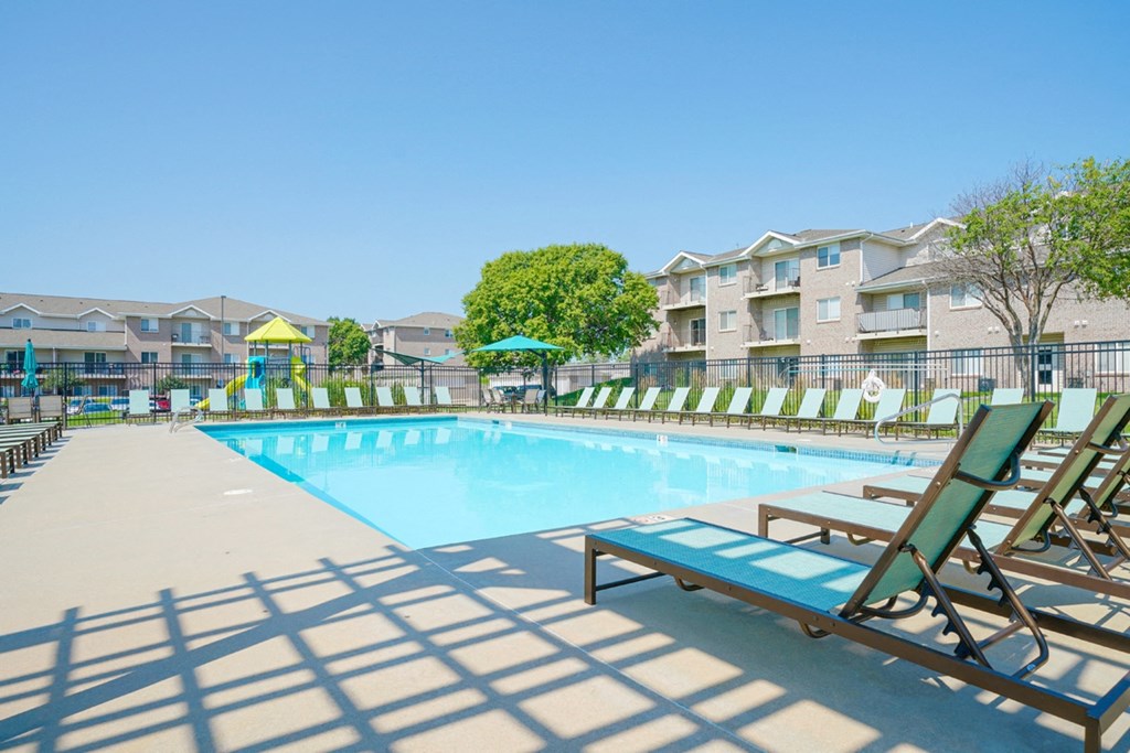 a rectangular pool with lounge chairs surrounding it
