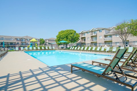 a rectangular pool with lounge chairs surrounding it