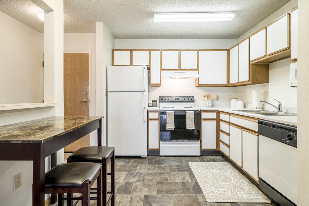 a kitchen with white appliances and a counter top with stools