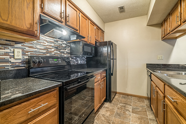 Renovated kitchen with updated appliances and dark wood cabinetry at Fountain Glen Apartments