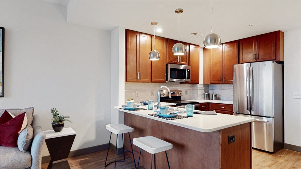 Kitchen with peninsula countertop, tile backsplash, and modern appliances in a 1 bedroom floor plan at Midtown Crossing Apartments Omaha