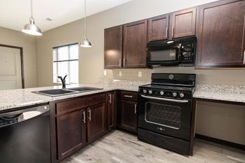 A kitchen with dark wood cabinets and black appliances.