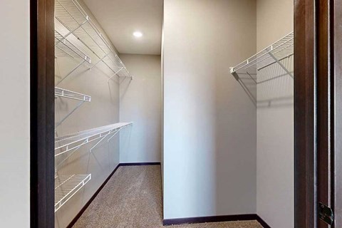 A long walk-in closet with built-in shelves along the left, and additional hanging space on the right.