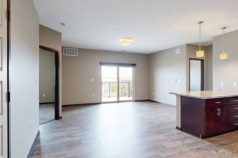 A spacious living area with neutral walls and wood-style flooring.