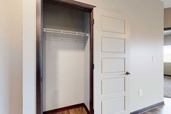 A coat closet with a built-in wire shelf for storage and hanging space.