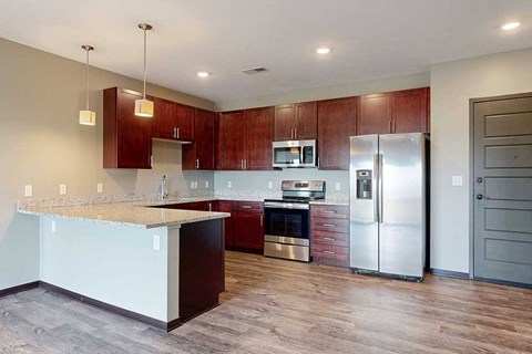 A modern kitchen with dark cabinetry, stainless steel appliances, and granite counters.