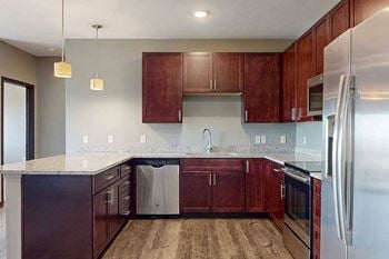 A modern kitchen with dark cabinetry, stainless steel appliances, and granite counters.