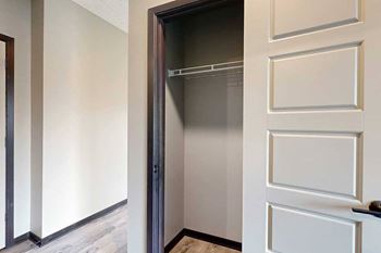 A hallway coat closet with a built-in wire shelf for hanging space.