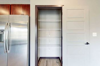 A pantry with built-in shelving next to a stainless steel fridge.