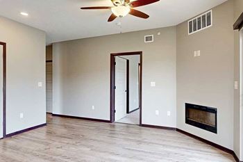 A living room with a ceiling fan, an electric fireplace, and wood-style flooring.