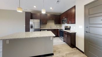 A kitchen with a granite countertop and warm brown wooden cabinets.