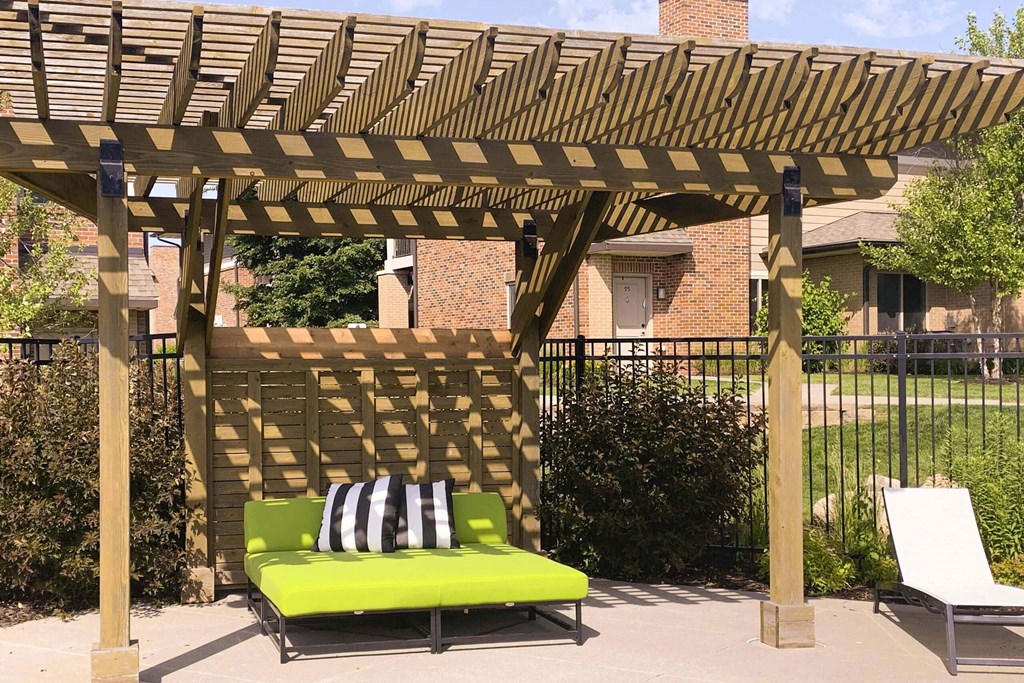 a patio with a green couch under a wooden pergola